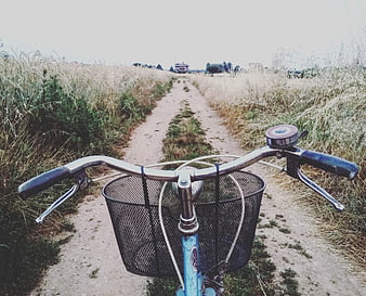 Vintage bicycle handlebars and basket on a rural dirt path
