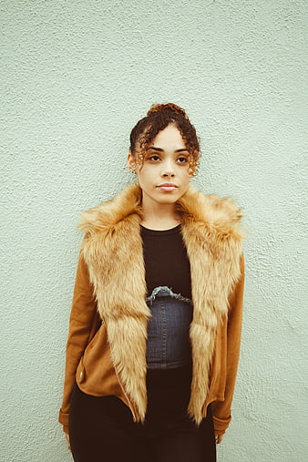 Woman in brown fur collar jacket against mint wall