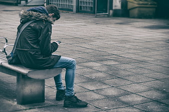 Man sitting on bench texting on smartphone in city