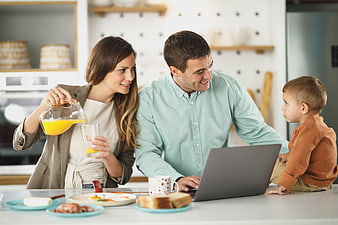 Happy family having breakfast with laptop in modern kitchen