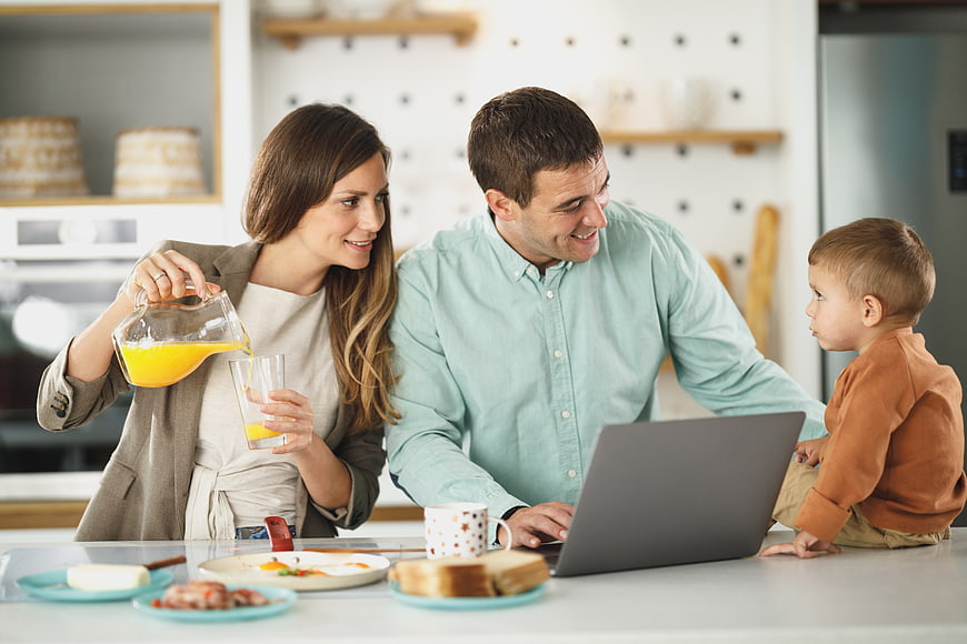 Happy family having breakfast with laptop in modern kitchen
