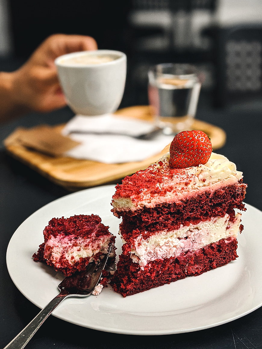 Slice of red velvet cake with strawberry and coffee