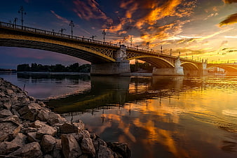 Dramatic Sunset Over Arched Bridge with Golden Reflections