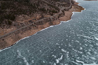 Aerial view of frozen lake with winding coastal road