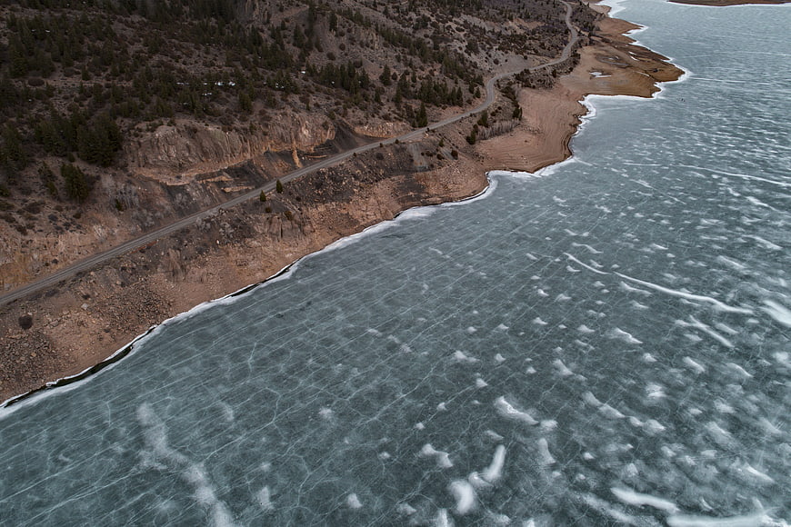 Aerial view of frozen lake with winding coastal road