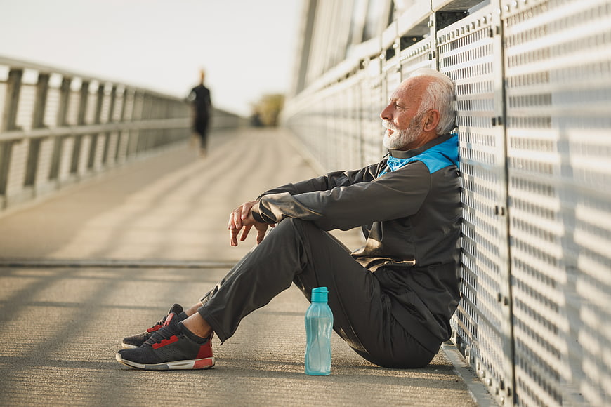 Senior man resting after running on bridge