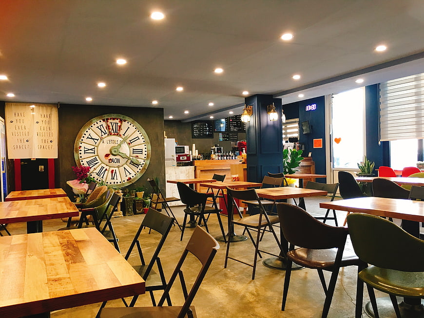 Modern Cafe Interior With Large Wall Clock And Wooden Tables