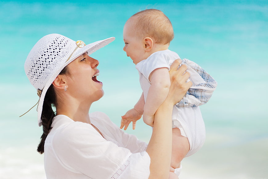 Happy Mother Holding Baby on Beach