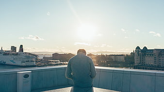 Man Sitting on Rooftop Overlooking Oslo Harbor at Sunset