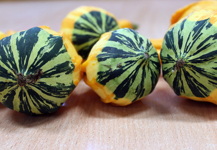 Close-up of decorative green and yellow striped pumpkins on wood