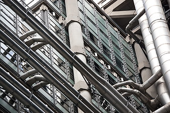 Low angle view of industrial pipes on modern building facade