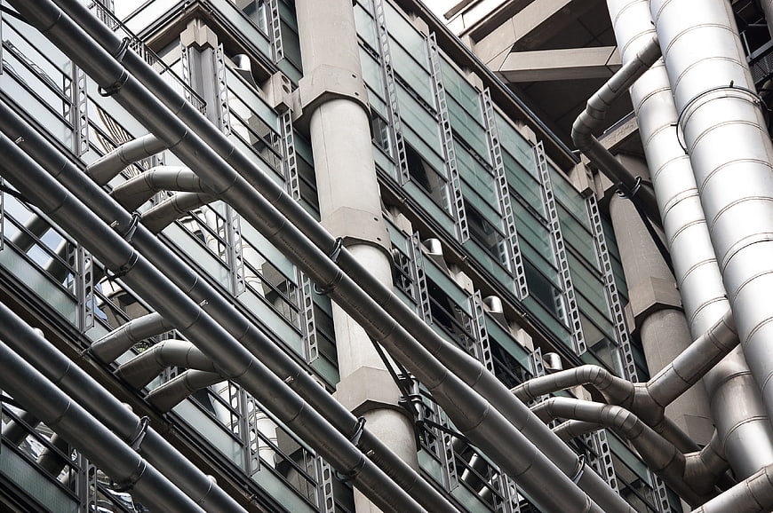 Low angle view of industrial pipes on modern building facade