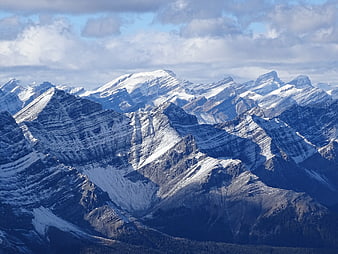 Snow-capped mountain range under cloudy blue sky