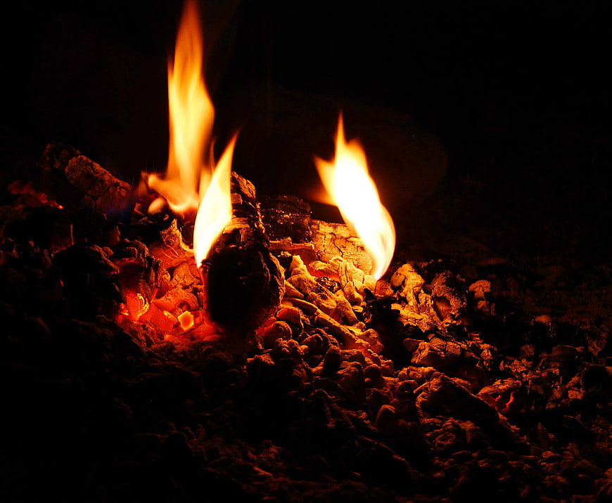 Close-up of burning charcoal and glowing embers in the dark