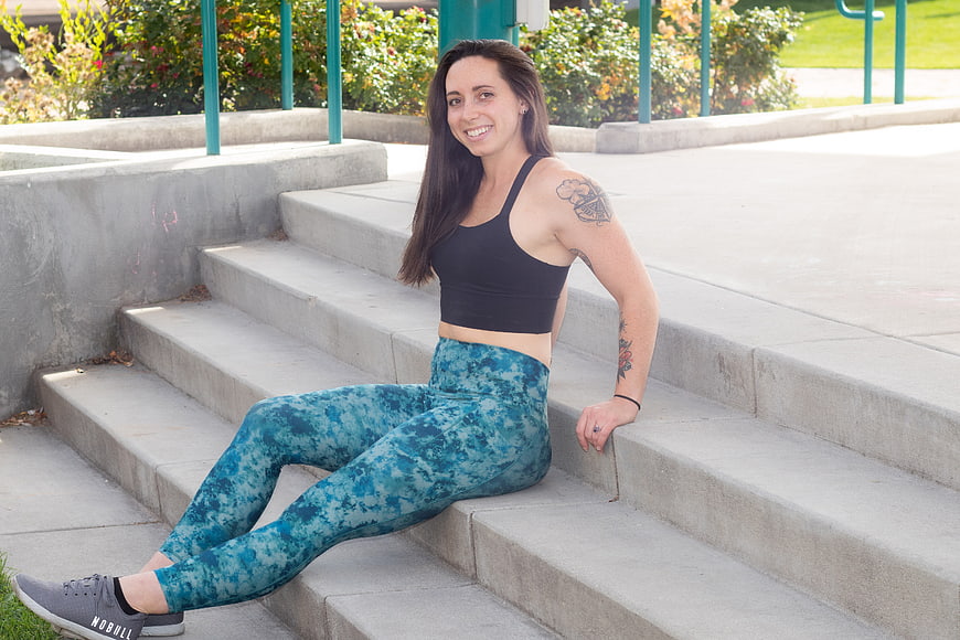 Smiling woman in workout clothes sitting on concrete steps