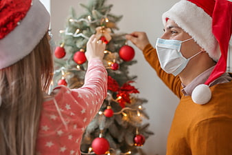 Couple wearing face masks decorating Christmas tree
