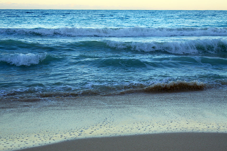 Calm Ocean Waves Rolling onto Sandy Beach at Sunset