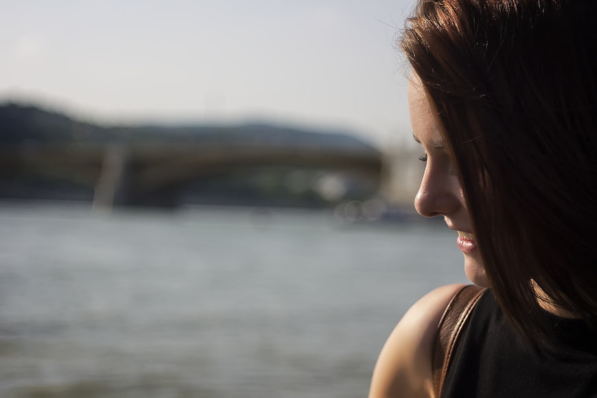 Profile of smiling woman looking out over river with bridge