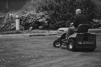 Senior Man Mowing Lawn on Riding Mower in Black and White