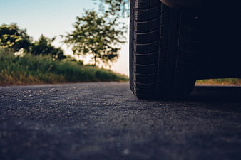 Low angle car tire on asphalt road with blurred nature background