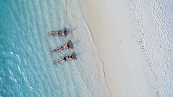 Aerial View of Three Women Relaxing on White Sand Beach