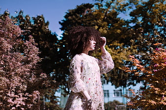 Woman with Curly Hair in Floral Dress in Autumn Park