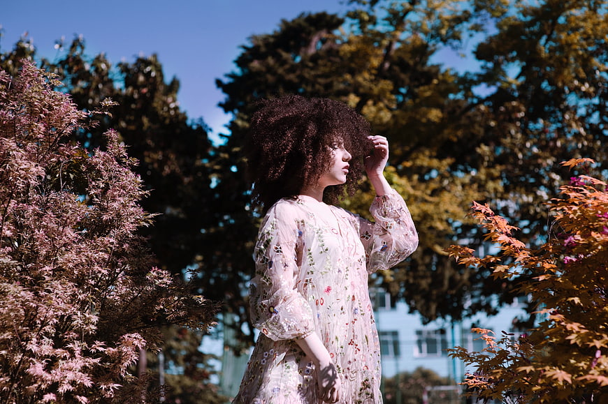 Woman with Curly Hair in Floral Dress in Autumn Park