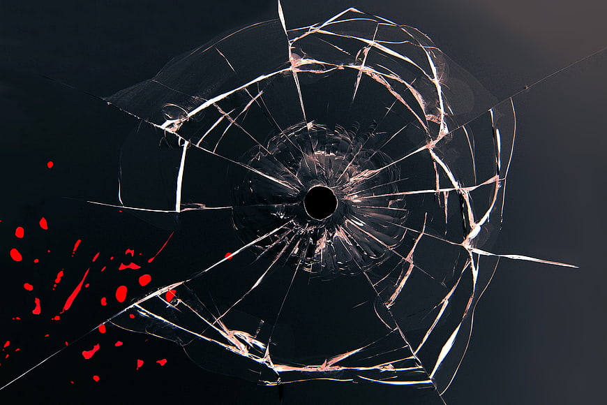 Shattered glass with bullet hole and red splatter on dark background