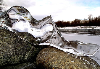 Transparent Ice Sculpture on River Rocks in Winter