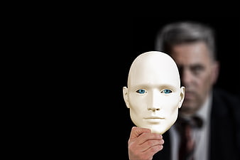 Businessman holding white mask against black background