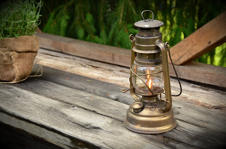 Vintage Kerosene Lantern Burning On Weathered Wooden Table