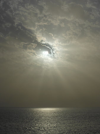 Dramatic sun rays breaking through clouds over the ocean