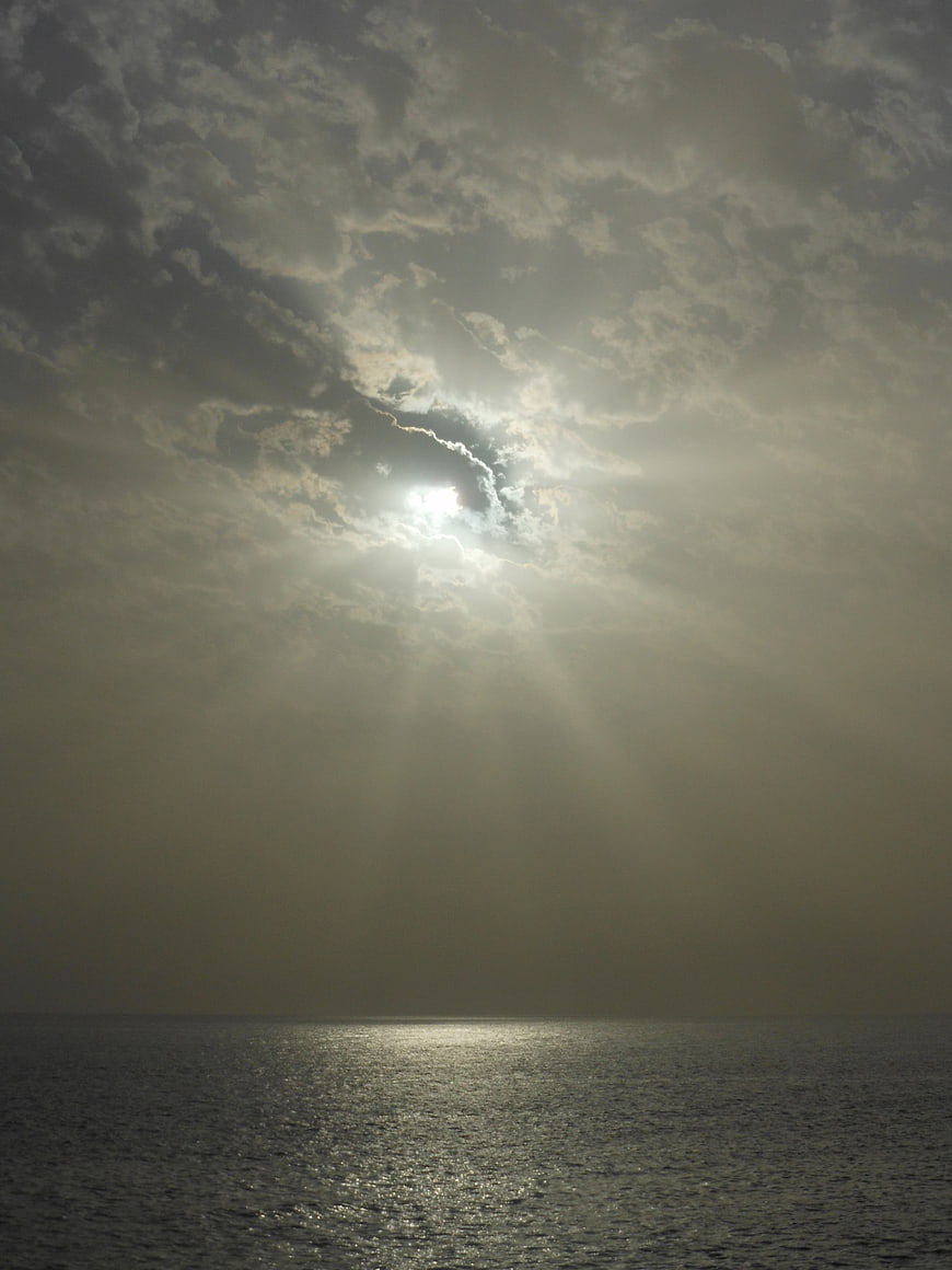 Dramatic sun rays breaking through clouds over the ocean