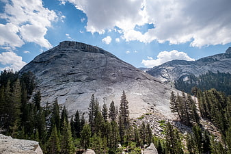 Majestic granite mountain peak with pine forest and blue sky