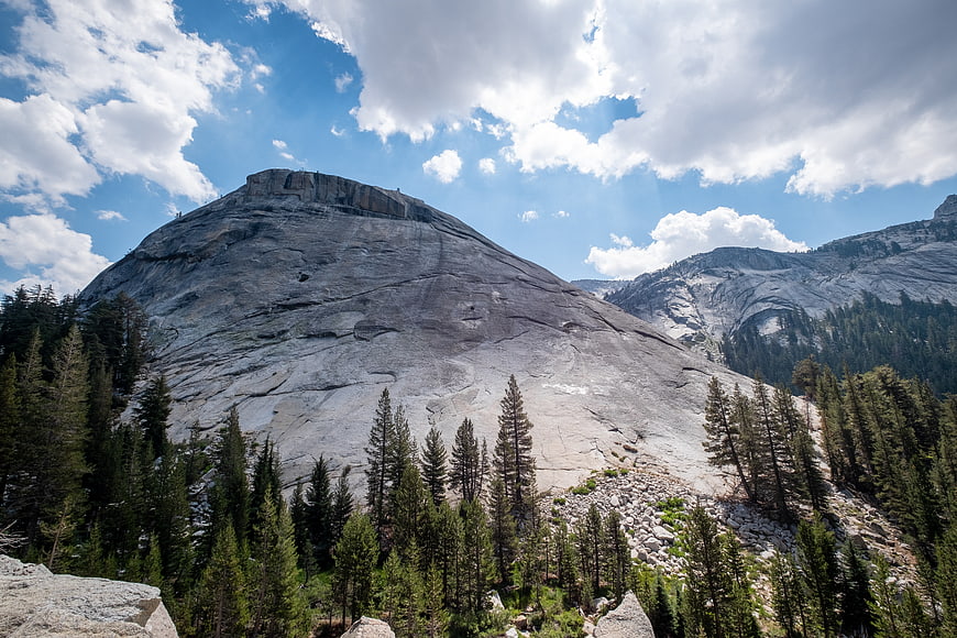 Majestic granite mountain peak with pine forest and blue sky