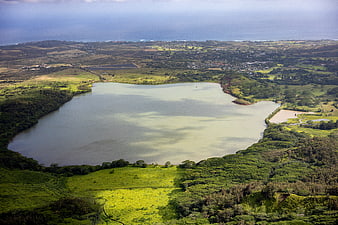 Aerial view of a serene lake surrounded by lush green hills