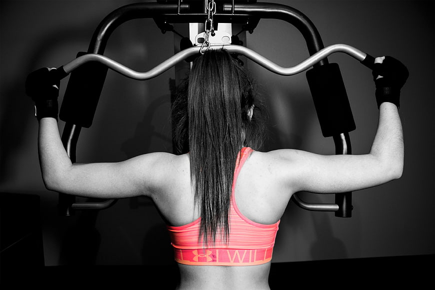 Woman performing lat pulldown exercise in gym