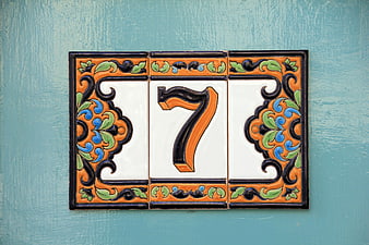 Decorative ceramic house number seven tile on blue wall