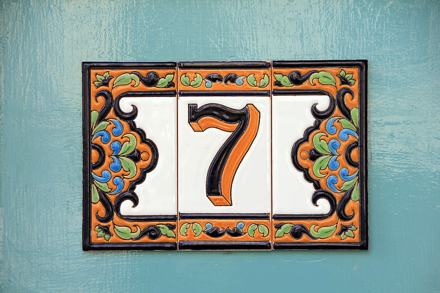 Decorative ceramic house number seven tile on blue wall