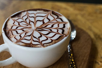 Close-up of Cappuccino with Intricate Latte Art on Wooden Table