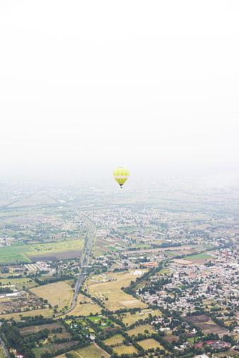 Aerial View of Yellow Hot Air Balloon Over Rural Landscape