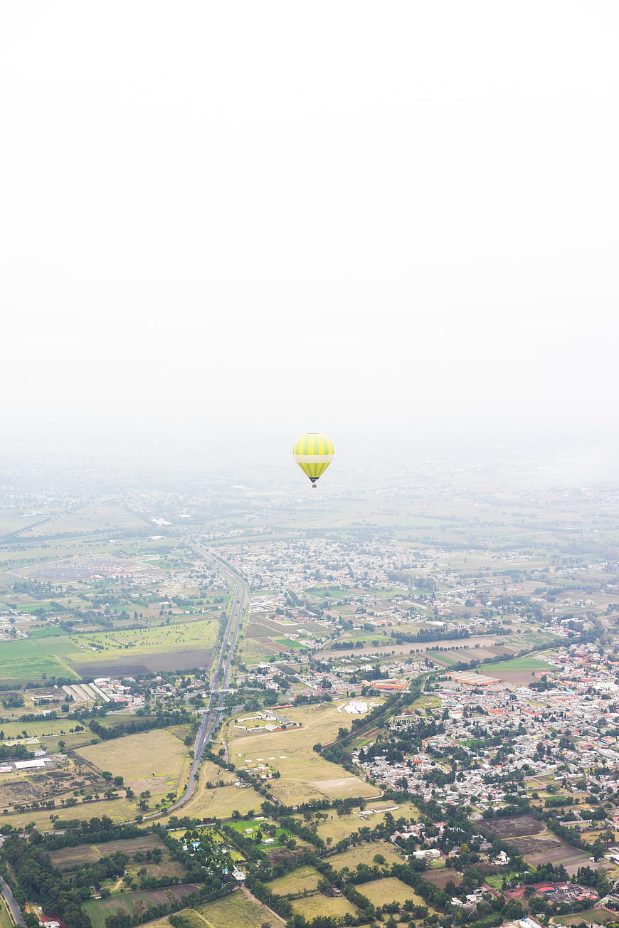 Aerial View of Yellow Hot Air Balloon Over Rural Landscape