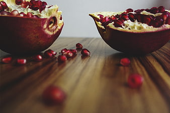 Fresh Pomegranate Halves on Wooden Table with Scattered Seeds