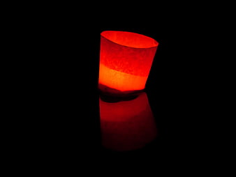 Glowing red floating candle on dark water surface