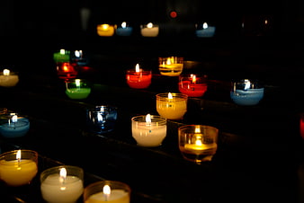 Colorful lit candles in glass holders on dark church steps