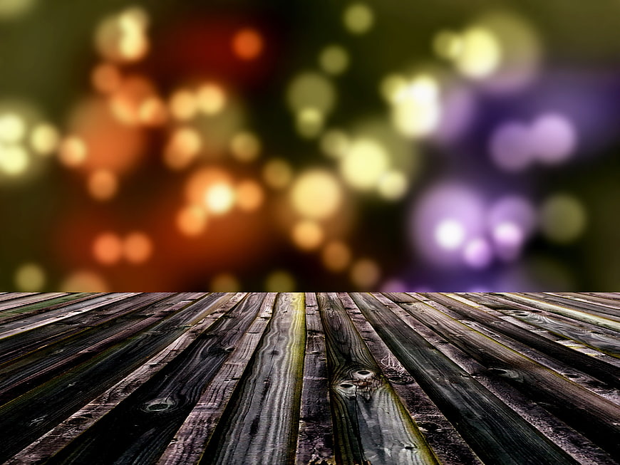 Rustic wooden table surface with colorful bokeh background