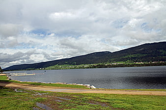 Serene lake landscape with forested mountains and cloudy sky