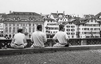 Three Men Sitting on Bridge in Black and White Cityscape