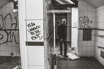 Man standing in abandoned tiled room with graffiti
