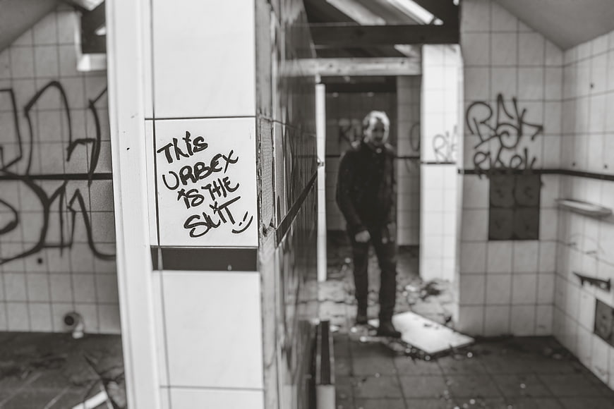 Man standing in abandoned tiled room with graffiti